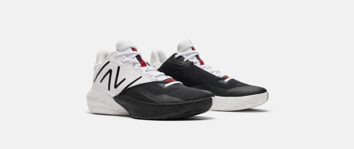 Side view of white, black, and red New Balance basketball shoes.